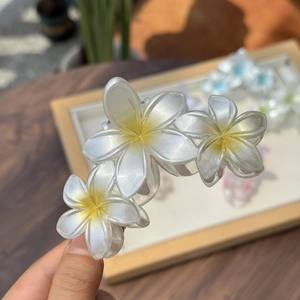 Pince à cheveux fleur de frangipanier nacrée pour une coiffure queue de cheval haute élégante