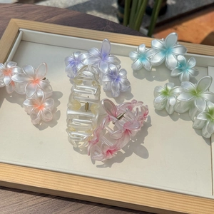 Vue détaillée des pinces à cheveux florales en résine pastel dans un plateau en bois