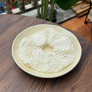 Chouchou en maille crochetée blanche avec motif ajouré sur une assiette