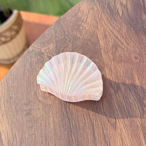 Iridescent laser seashell hair claw clip with colorful mermaid pearl finish on wood