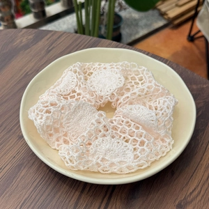 Chouchou en crochet crème fait main avec dentelle ajourée sur une assiette en céramique