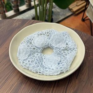 Détail d'un chouchou bleu clair crocheté à la main sur un plateau blanc en céramique
