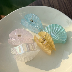 Detailed view of colorful seashell hair clips with holographic pearl finish and metal spring