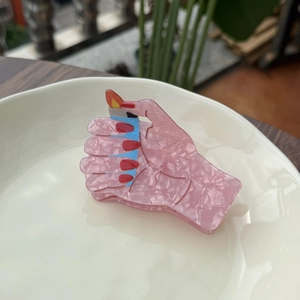 Unique pink acrylic hair claw shaped like a hand holding a lighter with orange flame