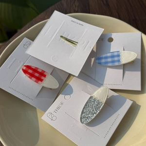 Detail view of oval acrylic hair clips with red blue checkers and silver sequins on card