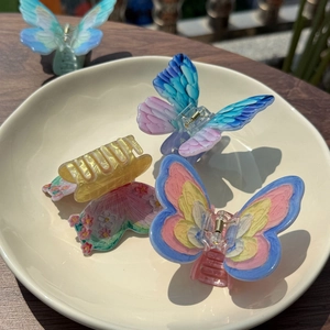 Detail of colorful acrylic butterfly hair claws with realistic wing texture and gradients