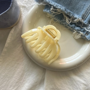 Elegant cream pumpkin hair claw clip for women on white ceramic tray background
