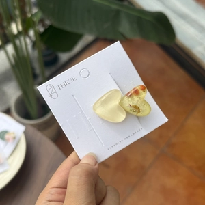 Dettaglio di fermagli per capelli a cuore in resina con fiori secchi e foglia d'oro