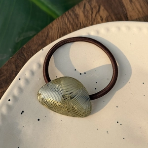 Detailansicht eines Vintage-Haargummis aus Bernstein-Harz mit goldener Handmade-Prägung