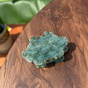 Detail of green acetate hair claw clip with traditional patterns on wooden surface