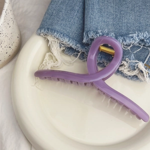 Gros plan sur une pince à cheveux violette française avec un ressort en métal doré