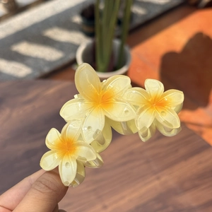 Détail de la pince à cheveux fleurs de frangipanier jaunes avec trois fleurs en résine