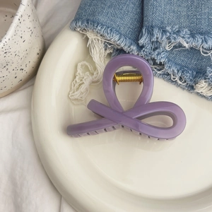 Vue de dessus d'une pince à cheveux violette brillante en forme de nœud sur une assiette