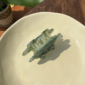 Light green acetate hair claw with vintage Chinese cloud pattern on a white tray