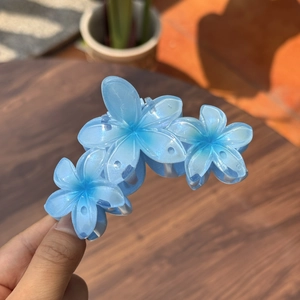 Détail de la pince à cheveux bleue avec fleurs en résine dégradée et fini scintillant