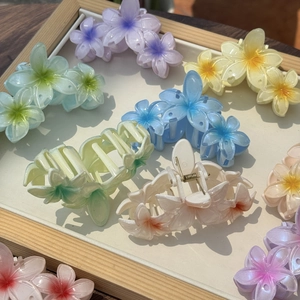 Détail des pinces à cheveux en résine de fleurs de frangipanier aux tons pastel