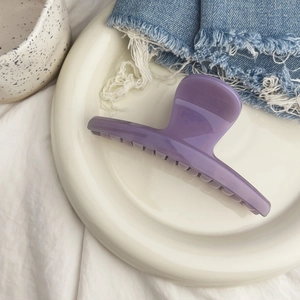 Détail de la pince à cheveux en résine violette translucide avec texture lisse et ressort