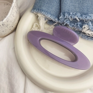Détail d'une pince à cheveux en résine violette brillante sur une assiette blanche