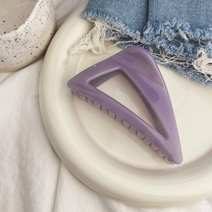 Gros plan d'une pince à cheveux triangulaire violette brillante sur une assiette