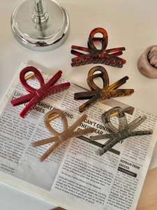 Dettaglio di cinque fermagli per capelli in acrilico a fiocco in rosso, ambra e tartaruga