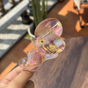 Detail view of octopus hair claw clip in iridescent pink acetate with gold trim