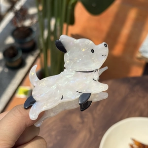 Detail van een witte parelmoer acetaat honden haarklem met zwarte accenten