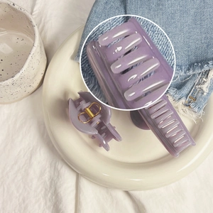 Détail de pinces à cheveux en résine violette sur assiette avec fond en denim