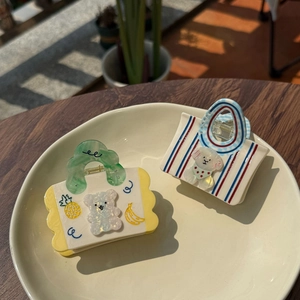 Détail de pinces à cheveux en acétate en forme de sac avec motifs ours et ananas