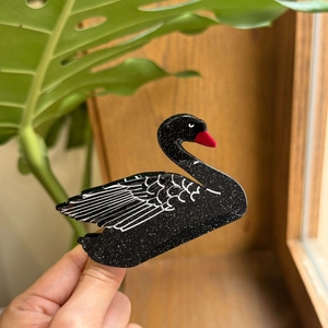 Vista dettagliata di un fermaglio per capelli a cigno nero con glitter argento e dettagli bianchi