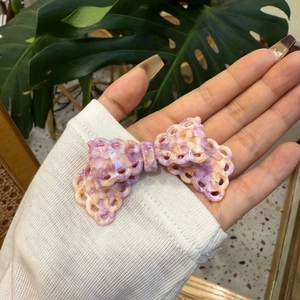 Dettaglio macro del fermaglio a fiocco in acetato Y2K con trama intrecciata 3D scavata