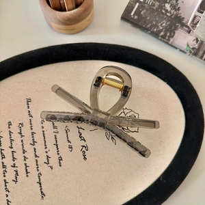 Pinza per capelli a fiocco grigio fumo minimalista su elegante sfondo di stoffa beige