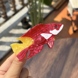 Detail of red and yellow acetate tropical fish hair claw clip with a glossy finish