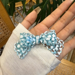 Dettaglio di un fermaglio per capelli a fiocco in pizzo blu e bianco in resina traslucida