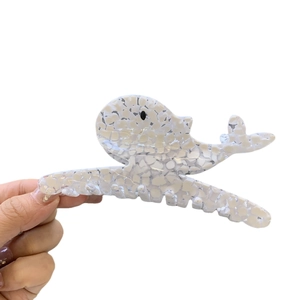 Whale shaped acetate hair claw clip with white marble texture held in hand