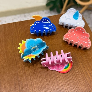 Close-up of five cute acrylic cloud hair claws with rhinestones and rainbow details