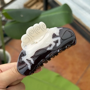 Elegant black and white acetate hair claw clip featuring a white horse relief pattern