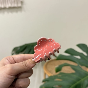 Pink cloud hair claw clip with rhinestones and smiley face in hand display
