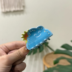 Detail of light blue cloud hair claw clip with smiley face and rhinestones decoration