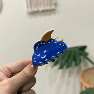 Close-up of cute blue cloud hair claw clip with white rhinestones and yellow moon detail