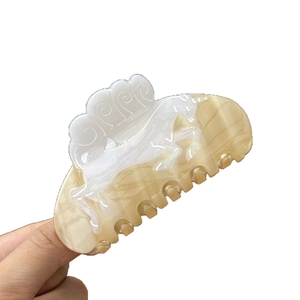 Hand holding a marble pattern acetate hair claw clip in cream and brown unicorn design