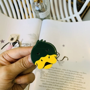 Close-up detail of a cute cartoon duck acetate hair clip in vibrant green and yellow