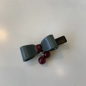 Detail of handmade bow hair clip with dark green resin and red beads pendant