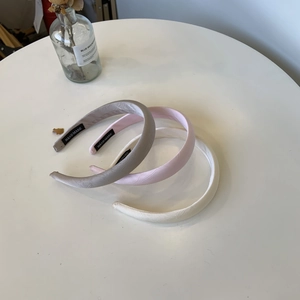 Detailed view of handmade padded headbands in grey, pink, and white with silky pearlescent texture