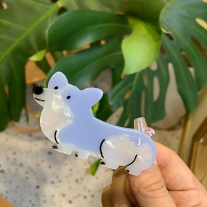 Χαριτωμένο κλιπ μαλλιών Corgi από οξική κυτταρίνη σε μωβ και λευκό σε πράσινο φόντο φύλλων