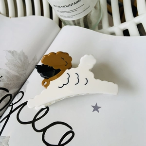 Close-up of a white and brown poodle-shaped acetate hair claw clip on a stylish table