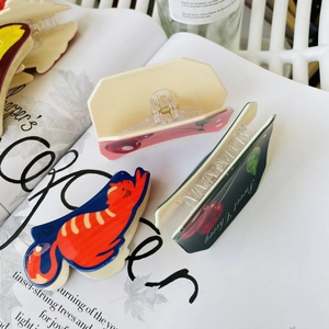 Flat lay of acrylic hair claws with cute orange cat and sweet cherry patterns