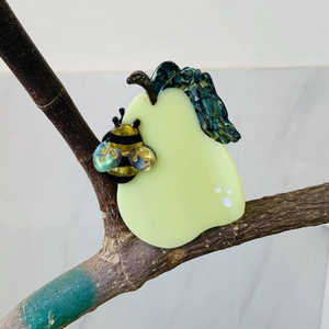 Pear and bee cellulose acetate hair claw clip hanging on a natural tree branch