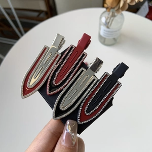 Detailed close-up of four rhinestone studded duckbill hair clips in red and black