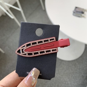 Close-up of a dark red rhinestone duckbill hair clip on a black card for display