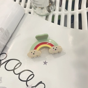 Detailed close-up of a mint green rainbow hair claw clip with smiling cloud motifs